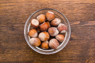 Obraz premium Hazelnuts on bowl on a wooden table viewed from above