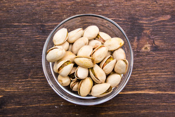 Pistachios on bowl on a wooden table viewed from above