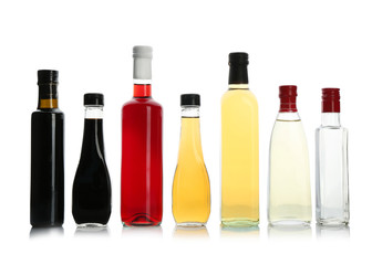 Bottles with different kinds of vinegar on white background