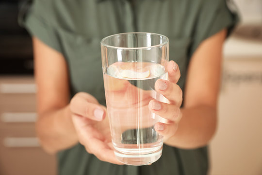 Woman holding glass with pure water in kitchen, closeup