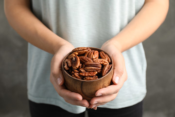 Woman holding bowl with shelled pecan nuts in hands, closeup - obrazy, fototapety, plakaty