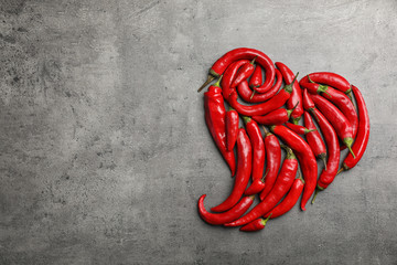 Heart shape made of red chili peppers on gray background, top view with space for text - obrazy, fototapety, plakaty