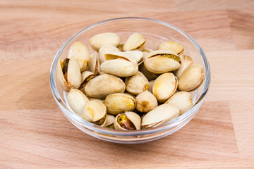 Pistachios on bowl on a beech wood table