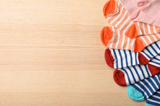 Cute child socks on wooden background, top view. Space for text