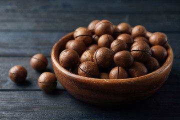 Bowl with organic Macadamia nuts on blue wooden background