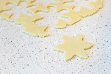 Raw sugar cookie dough rolled out on a light colored granite countertop, with snowflake cookies cut out