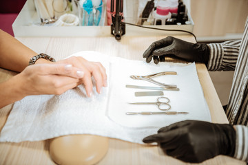 All the instruments. Manicure master wearing black gloves and striped blouse preparing all the instruments