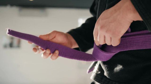 Karate purple belt tied around marital artists torso wearing black dojo GI's jiu jitsu mma fighter wearing gym ring