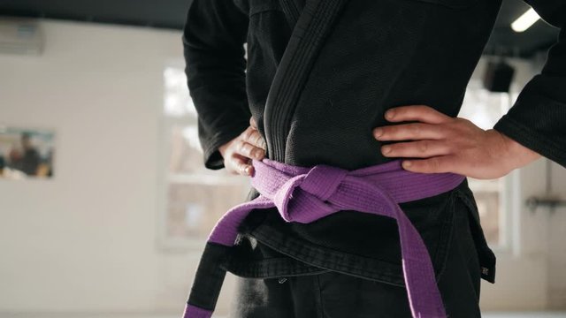 Karate purple belt tied around marital artists torso wearing black dojo GI's jiu jitsu mma fighter wearing gym ring