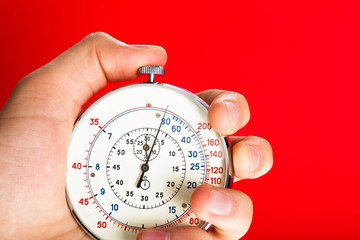 Close Up Of Hand Holding Stopwatch on Red Blackground