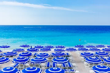 Vlies Fototapete Nice Blue umbrellas and chairs on beach by blue sea, in Nice, France