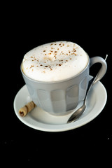 Delicious Cappuccino served with chocolate hazelnut wafer roll isolated black background