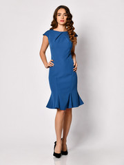 Fototapeta premium Young beautiful woman posing in new dark blue fashion winter dress on a white