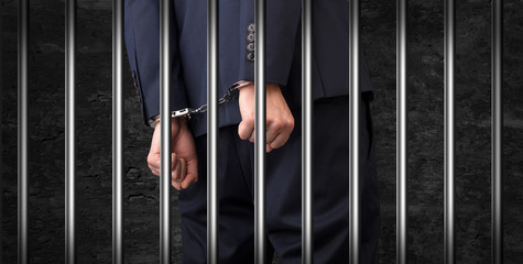 Close convicted man with handcuffs behind grids