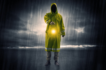 Raincoated man walking in storm with glowing lantern in his hand

