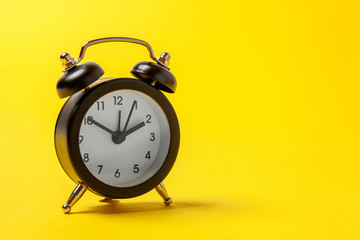 Ringing twin bell vintage classic alarm clock isolated on yellow colourful trendy modern fashion...