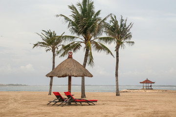 Red beach lounge chairs under tents on the tropical sandy beach, perfect idyllic tropical vacation concept