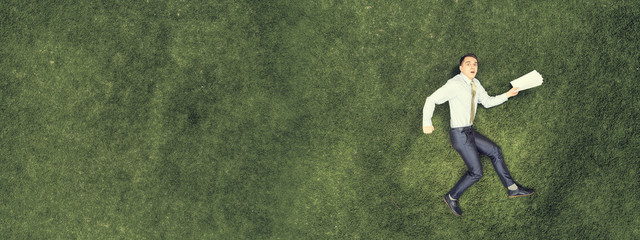 Pensive businessman on grass