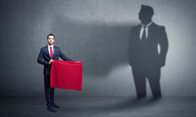Obraz premium Businessman standing with red cloth on his hand and his shadow on the background 