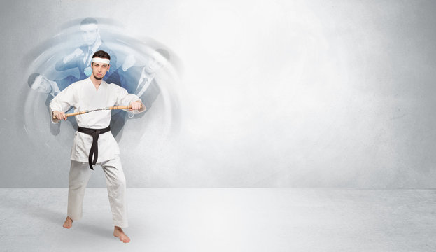 Young businessman in suit fighting with empty wall background
