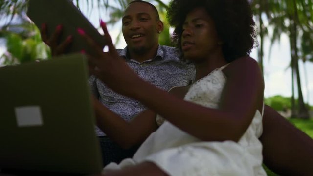 Young Black Couple Using Technology in the Park. Laptop, Tablet, phone. Miami beach Florida US