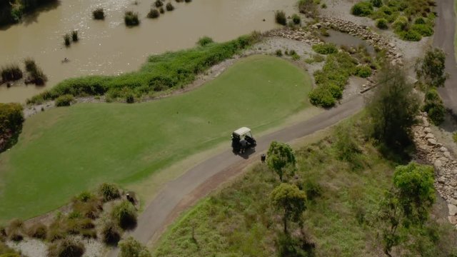 A golfer getting ready to tee off with his golf cart on the green.