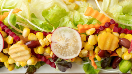 Corn, beetroot, carrot, red bean, and lettuce on a white plate.