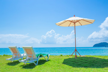 Beach chairs and beach umbrellas are on the lawn at the beach.Sea view and bright sky.