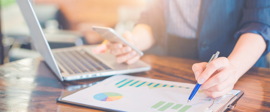 Business woman working on analysis charts and graphs showing results.Her hand holds the pen and points to the graph.