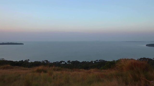 Time lapse of sunset over Lake Victoria. View of archipelago (Ssese Islands) from hill in Kalangala, Uganda. Gusts of wind on water, islands and horizon showing.