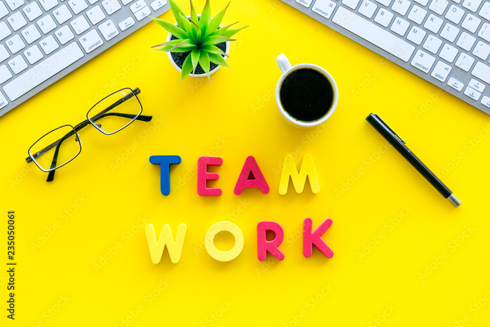 Poster teamwork in office. text team work lined with colored letters on yellow office desk with computer ke