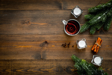 Winter beverage for New Year or Christmas Eve. Mulled wine near fir branches, candles, cinnamon on dark wooden background top view space for text