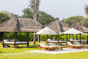 Fototapeta premium Wooden beach lounge chairs under tents on the tropical beach, perfect idyllic tropical vacation concept