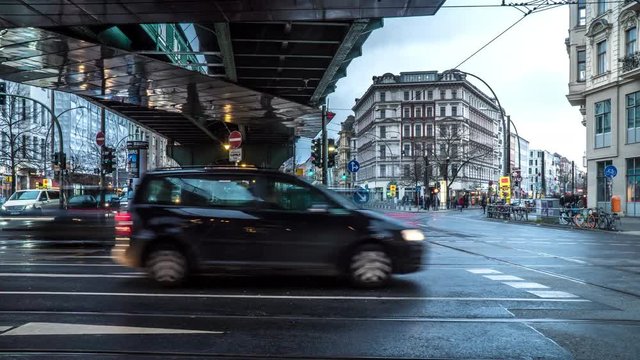 Berlin crossroad with fast moving people and vehicles on a rainy day - 4k