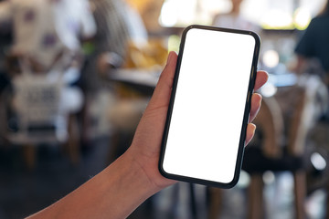 Mockup image of a hand holding black mobile phone with blank desktop screen with blur background in cafe