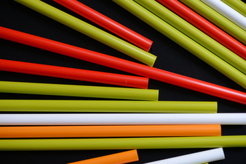 Colorful plastic straws on a dark background close up