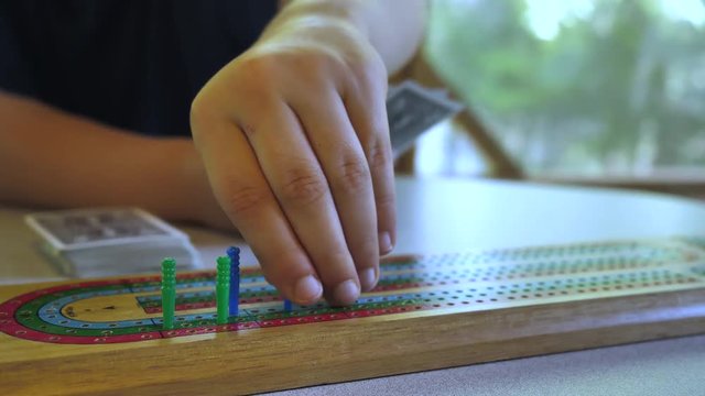 Close up of moving a peg on a cribbage board.