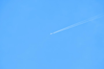Airplane flying with white contrail in the blue sky. Minimal background.