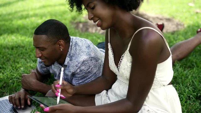 Young Black Couple Using Technology in the Park. Laptop, Tablet, phone. Miami beach Florida US