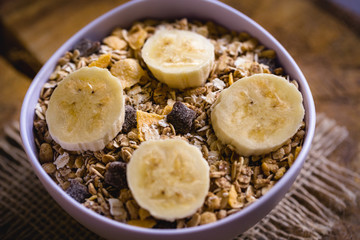 Bowl of cereal with fruit, pieces of banana with oats and cereal.