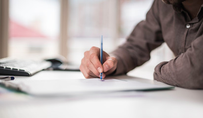 Happy young man, wearing glasses, as he works on his computer to get all his business done early in the morning
