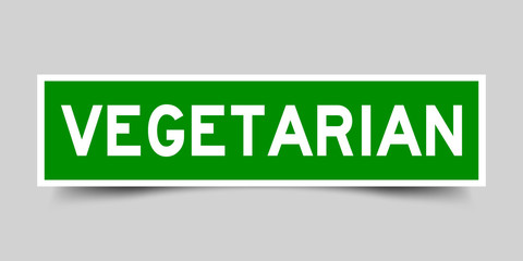 Square green sticker label in word vegetarian on gray background