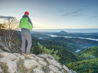 Man stands alone on the peak of rock. Hiker watching to autumn