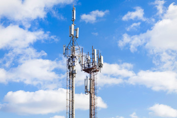 Two cell towers against the blue sky with clouds. Mobile communications and communications.