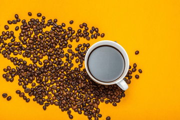 Spilled coffee beans on a bright yellow background