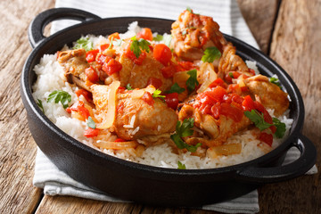 Fototapeta na wymiar Haitian recipe for spicy chicken cooked in vegetable sauce with white wine served with white rice in a frying pan closeup. horizontal