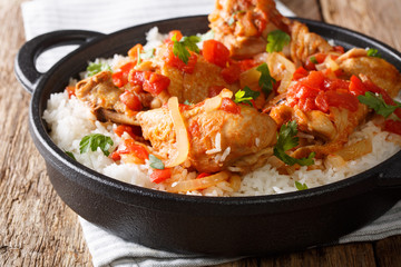 Haitian chicken stewed in a spicy tomato sauce served with white rice close-up in a pan. horizontal