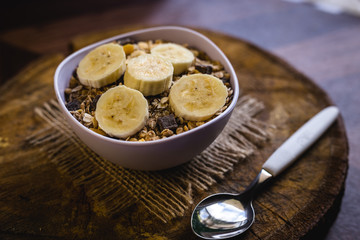 Bowl of cereal with fruit, pieces of banana with oats and cereal.