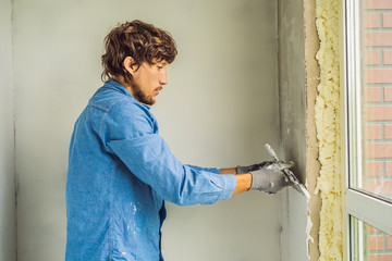 master is applying white putty on a wall and smearing by putty knife in a room of renovating house...
