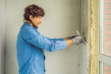 master is applying white putty on a wall and smearing by putty knife in a room of renovating house...